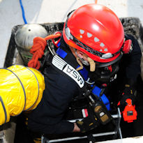 Worker wearing PPE entering confined space with forced air in use