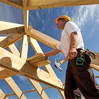 Construction worker with hammer looking at wood beams