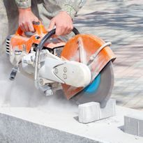 Worker using circular saw to cut masonry bricks
